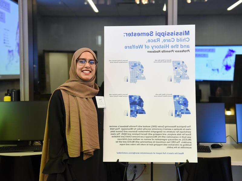 Woman wearing a hijab next to her poster presentation